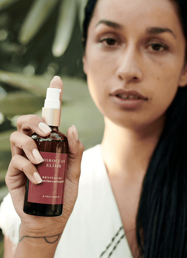 Model holding Revitalize hair oil - Moroccan Elixir